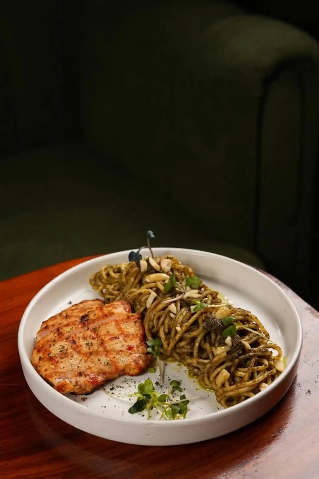 Seasoned salmon fillet with pesto noodles and microgreens