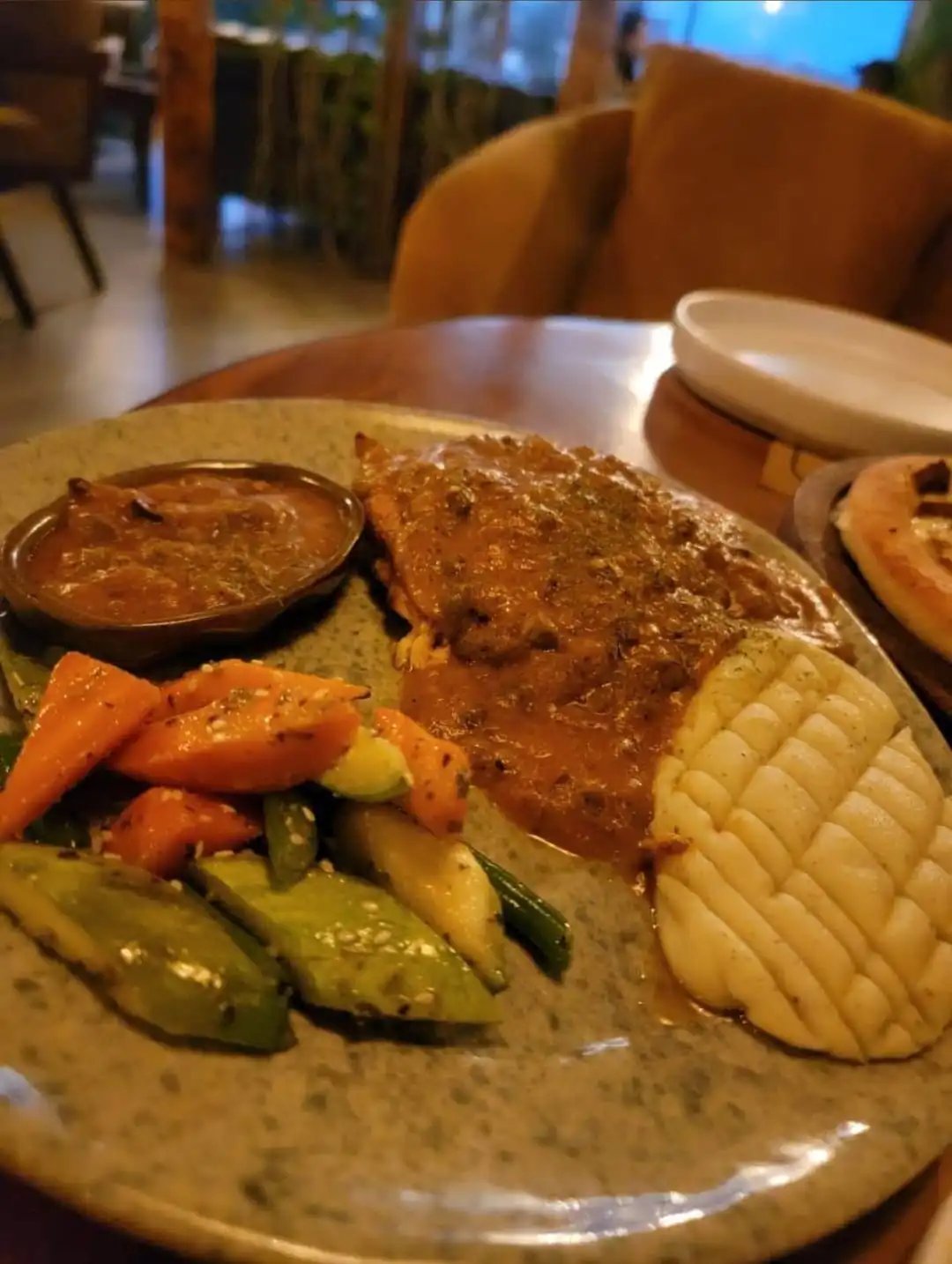 Plated grilled steak with a rich brown sauce, served with corn on the cob and mixed vegetables at KAV
