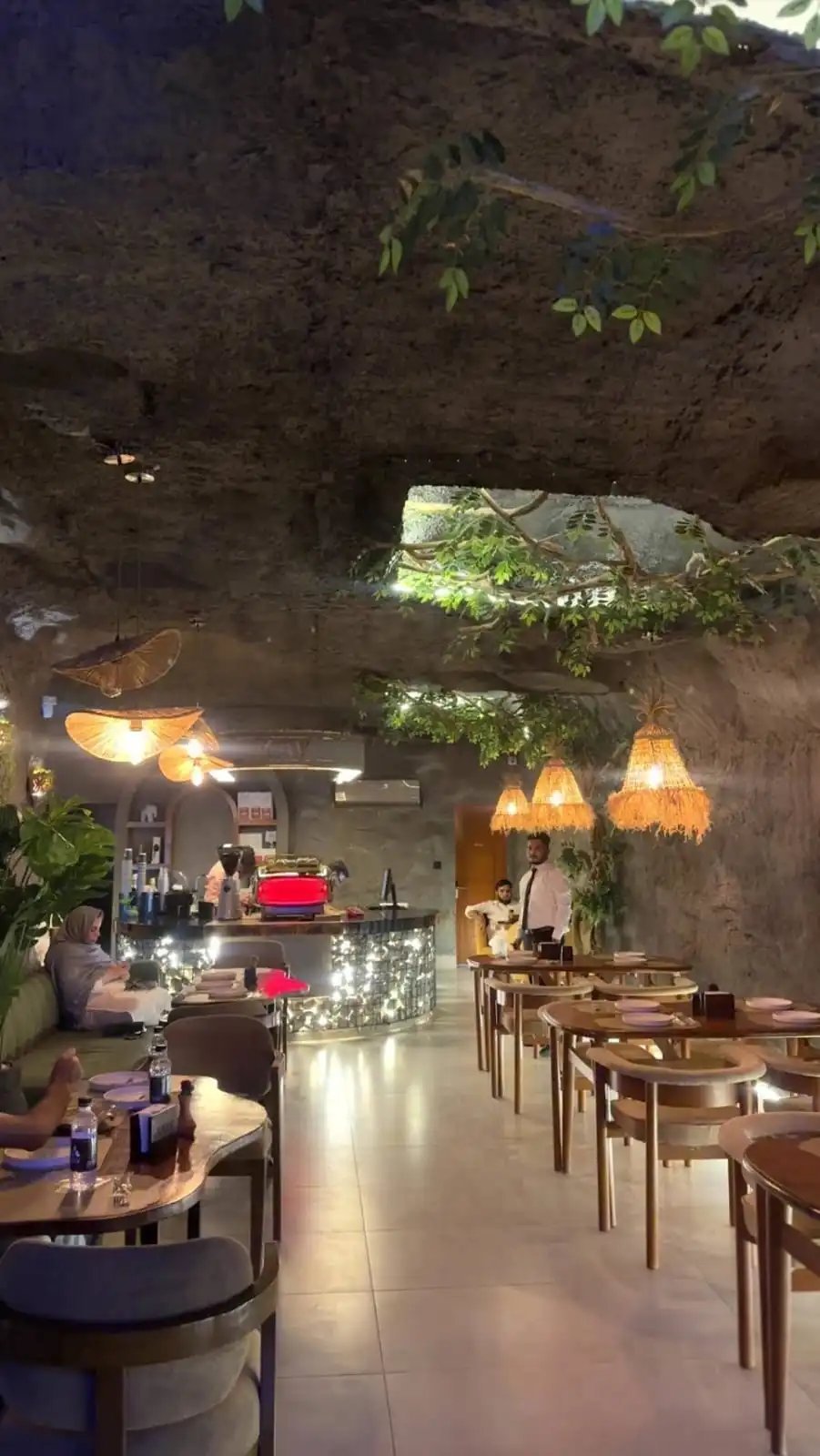 KAV cave-style dining room with rustic stone ceiling, pendant lights, wooden tables and a counter area with patrons dining
