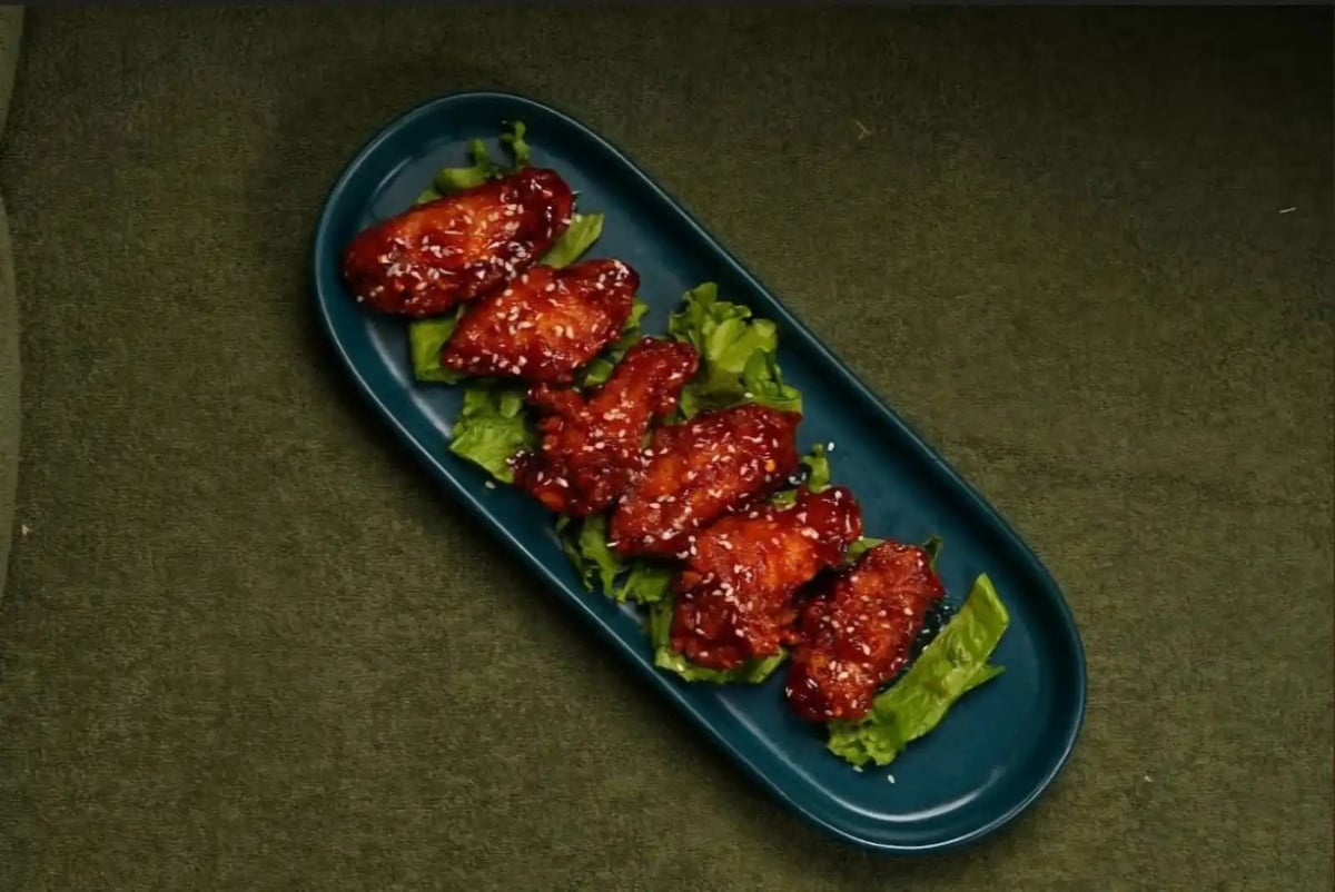 Glazed sesame meatballs served on a blue oval plate with fresh lettuce