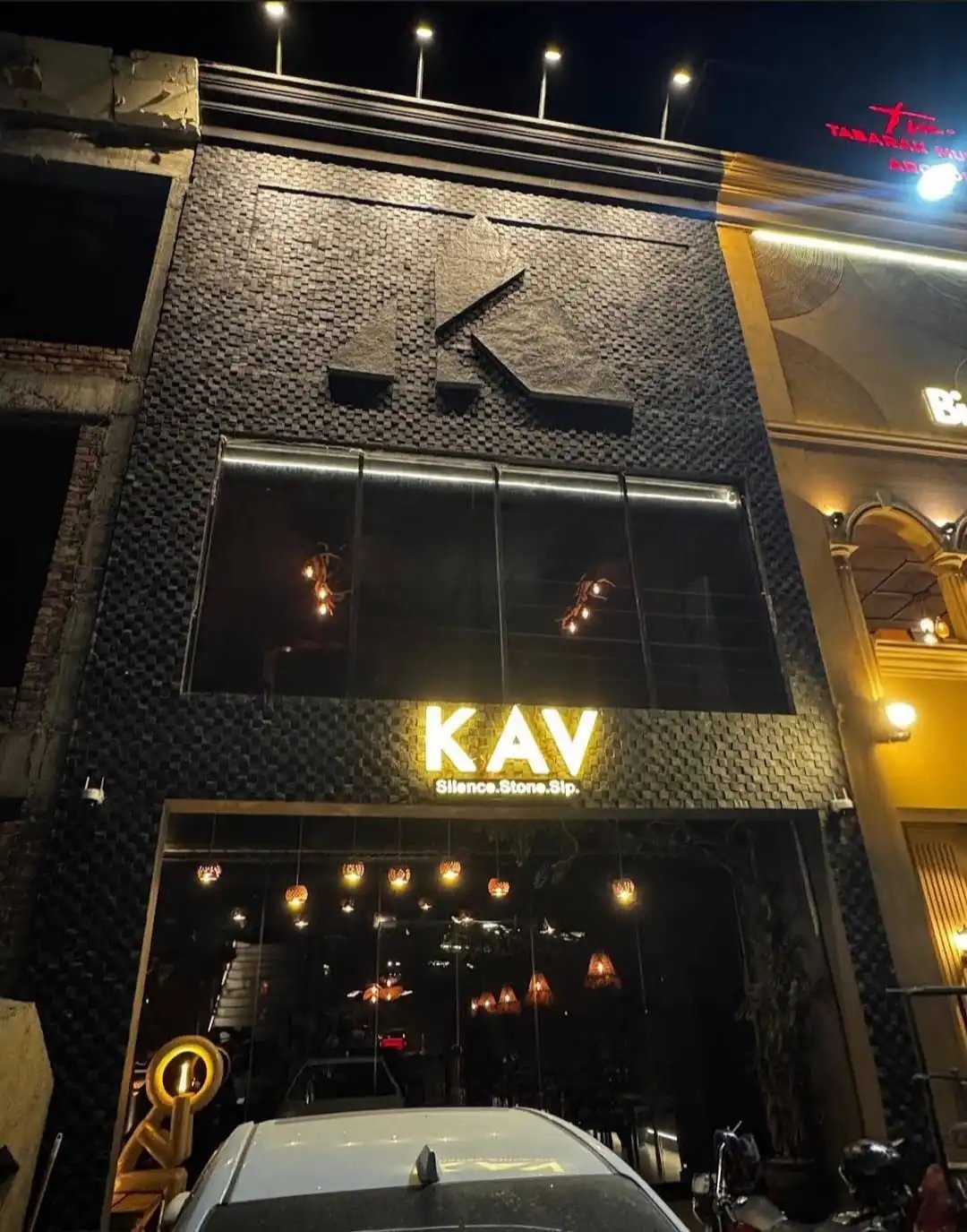 KAV restaurant storefront at night with illuminated KAV signage and large windows