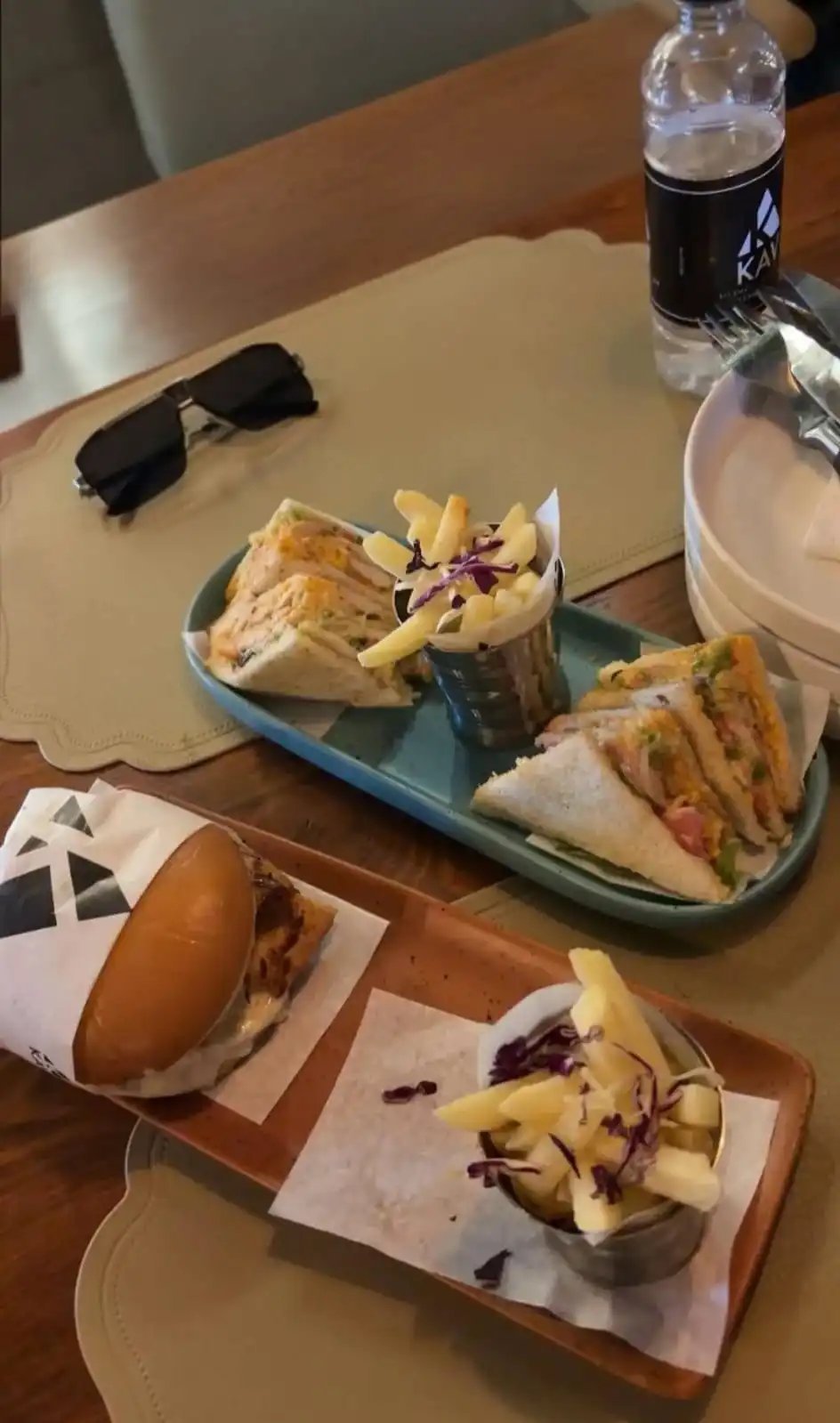 KAV table with club sandwich wedges and a burger, served with KAV-branded fries and a KAV water bottle